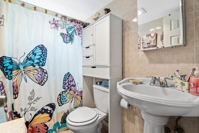 bathroom with tile walls and toilet