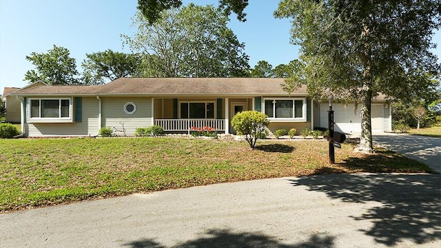 single story home featuring covered porch, a front lawn, and a garage