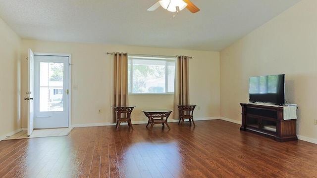 living area featuring ceiling fan and dark wood-type flooring