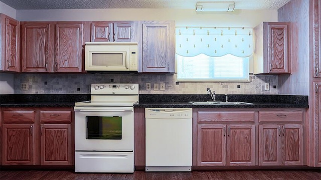 kitchen with white appliances, dark stone countertops, dark wood-type flooring, and sink