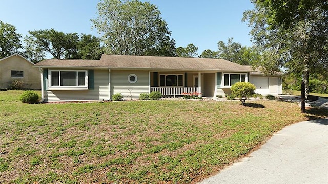 ranch-style home featuring covered porch, a front lawn, and a garage