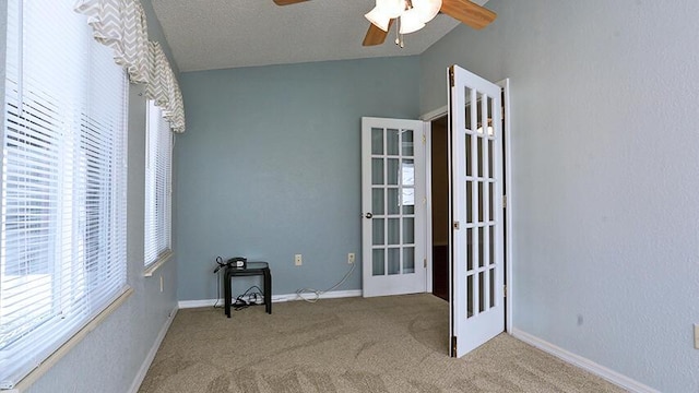 spare room with lofted ceiling, ceiling fan, light carpet, a textured ceiling, and french doors