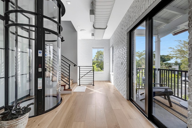 foyer featuring brick wall, light hardwood / wood-style floors, and french doors