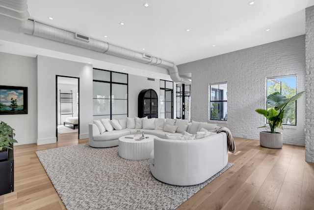 living room with brick wall and light hardwood / wood-style flooring