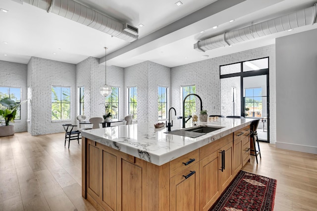 kitchen featuring a breakfast bar area, a center island with sink, a healthy amount of sunlight, and hanging light fixtures