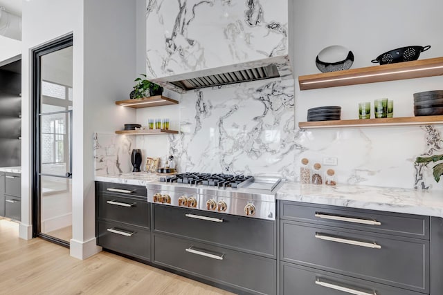 kitchen with light stone countertops, custom exhaust hood, light hardwood / wood-style floors, gray cabinets, and gas cooktop