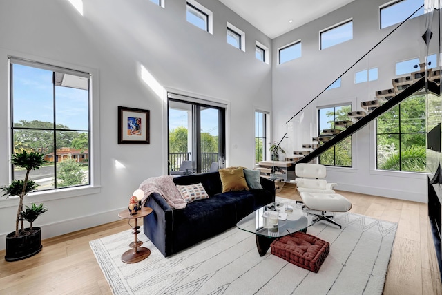 living room with light hardwood / wood-style floors and a towering ceiling