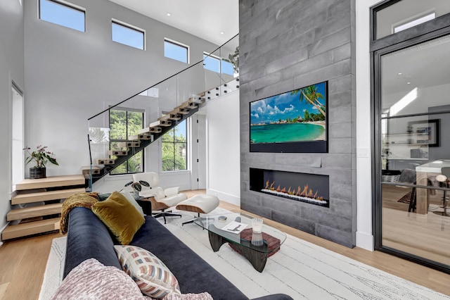 living room with light hardwood / wood-style floors, a towering ceiling, and a fireplace