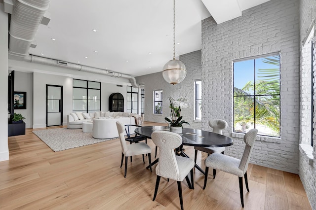 dining area with brick wall and light wood-type flooring