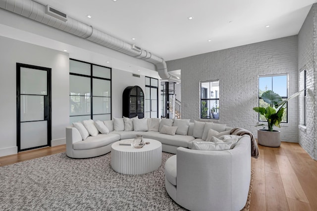 living room featuring brick wall and light hardwood / wood-style floors