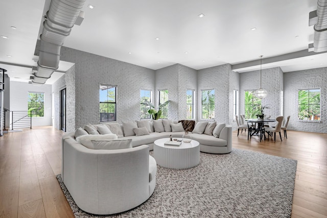 living room featuring brick wall, light hardwood / wood-style floors, and a wealth of natural light