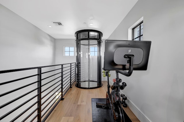 exercise area featuring a chandelier and light wood-type flooring