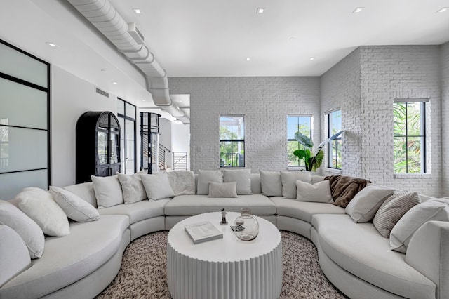 living room featuring brick wall and a wealth of natural light