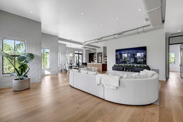 living room with brick wall and light wood-type flooring