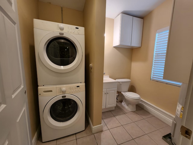 clothes washing area with stacked washer / drying machine and light tile floors