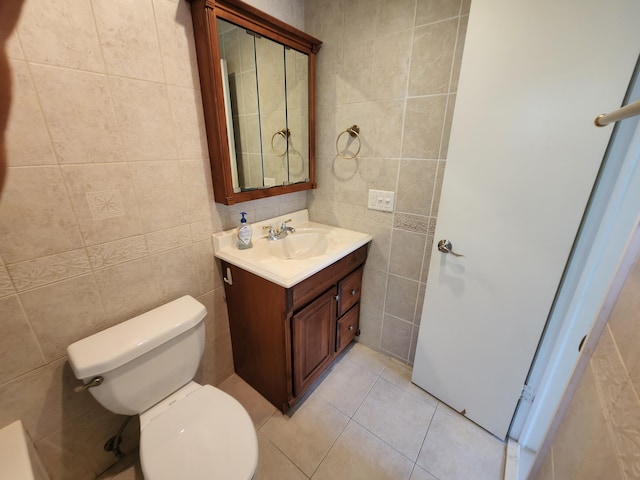 bathroom with tile walls, toilet, large vanity, and tile flooring