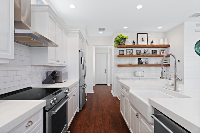 kitchen with backsplash, wall chimney exhaust hood, white cabinets, and appliances with stainless steel finishes