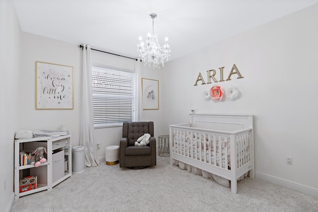 bedroom with light colored carpet, a crib, and a notable chandelier