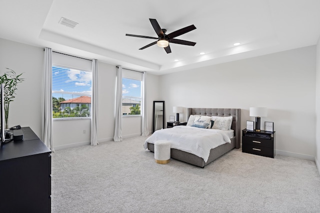 carpeted bedroom featuring a raised ceiling and ceiling fan