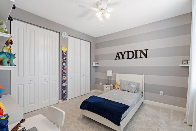 carpeted bedroom featuring multiple closets and ceiling fan