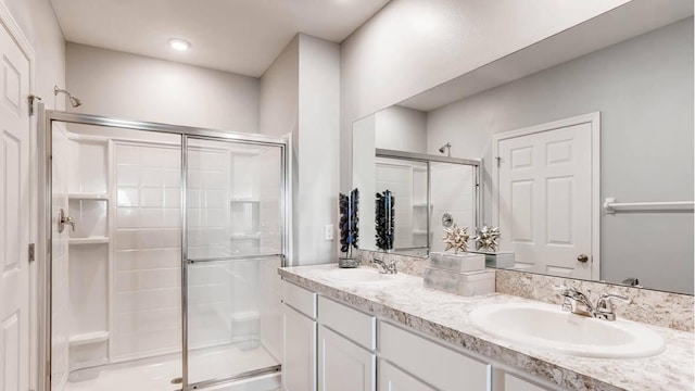 bathroom featuring oversized vanity, double sink, and a shower with door