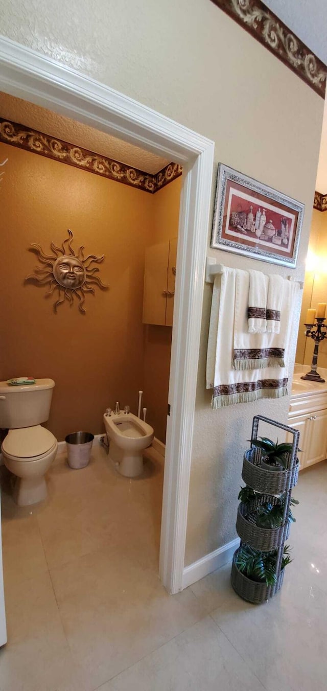 bathroom featuring toilet, a bidet, tile flooring, and ornamental molding