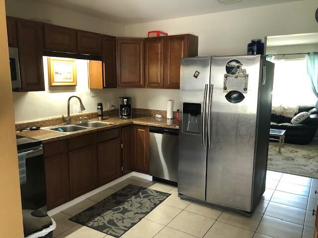 kitchen with light tile floors, appliances with stainless steel finishes, dark brown cabinets, and sink