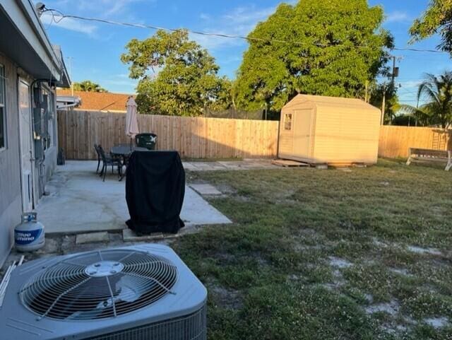 view of yard with a patio area, central AC, and a storage unit