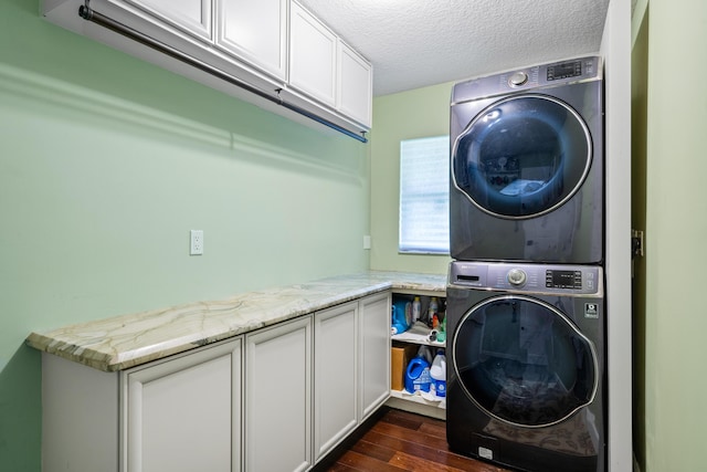 laundry area with cabinets, stacked washer and dryer, a textured ceiling, and dark hardwood / wood-style flooring