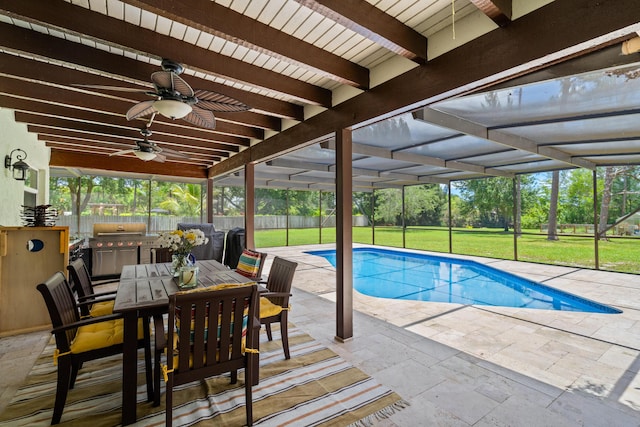 view of pool with a patio area, ceiling fan, a yard, glass enclosure, and exterior kitchen