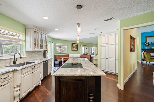 kitchen featuring hanging light fixtures, backsplash, dark wood-type flooring, sink, and a kitchen island