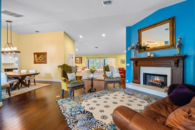 living room with a tiled fireplace, dark hardwood / wood-style floors, and vaulted ceiling