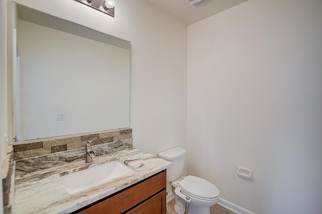 bathroom with toilet, vanity, and tasteful backsplash