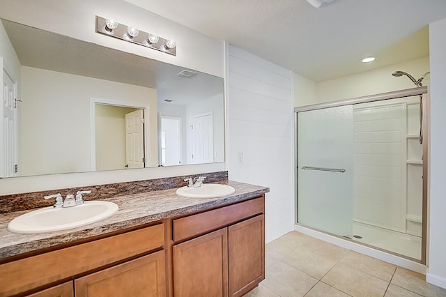 bathroom featuring walk in shower, double vanity, and tile floors