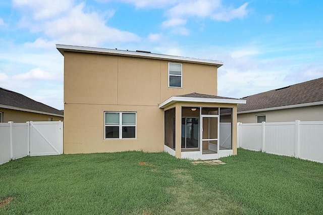 back of house featuring a lawn and a sunroom