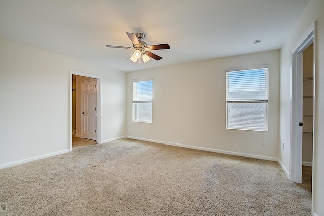 carpeted spare room featuring plenty of natural light and ceiling fan