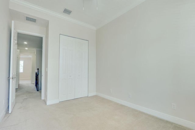 unfurnished bedroom with light carpet, ornamental molding, and a closet