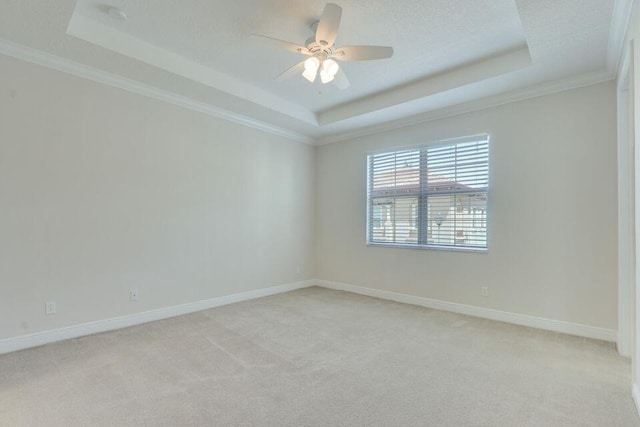 spare room featuring crown molding, a tray ceiling, ceiling fan, and light colored carpet