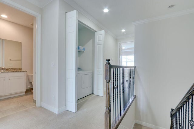 hallway featuring crown molding, light colored carpet, sink, and washing machine and dryer