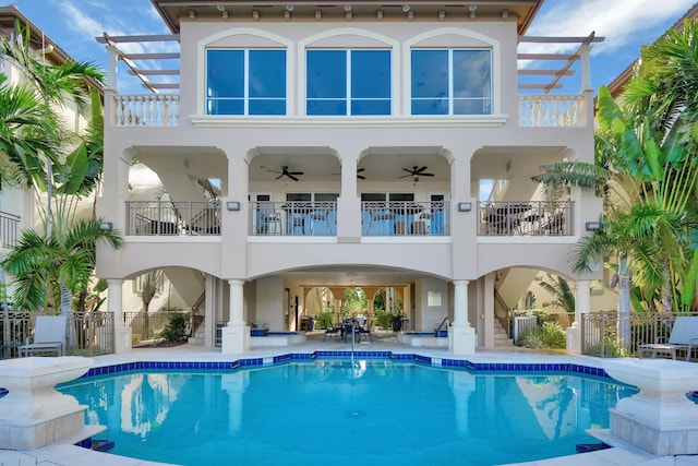 rear view of property with a balcony, a fenced in pool, and ceiling fan