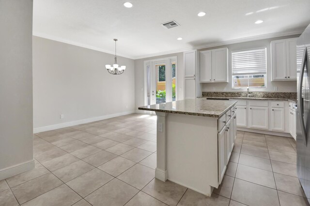 kitchen with stone countertops, light tile floors, white cabinets, a chandelier, and a kitchen island