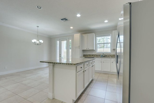 kitchen featuring stainless steel fridge, light tile floors, a kitchen island, a notable chandelier, and white cabinetry