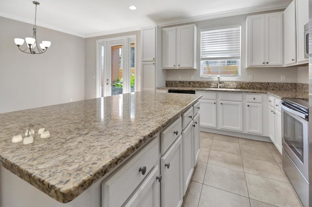 kitchen featuring white cabinets, a notable chandelier, a healthy amount of sunlight, and light tile floors