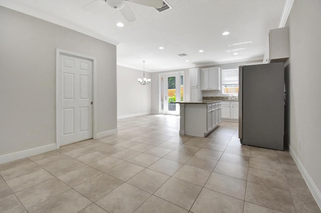 kitchen with white cabinetry, ceiling fan with notable chandelier, light tile flooring, a kitchen island, and pendant lighting