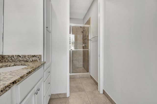 bathroom with tile floors, a shower with shower door, and vanity