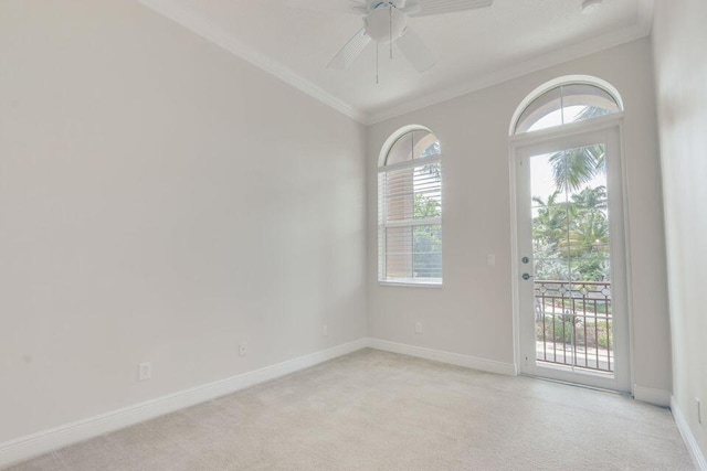 carpeted empty room with ceiling fan, a wealth of natural light, and ornamental molding