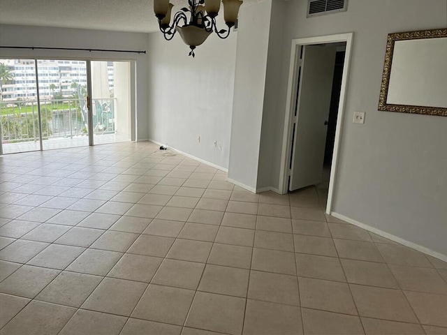 tiled empty room featuring a chandelier