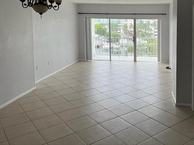 tiled spare room featuring a notable chandelier