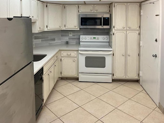 kitchen with light tile flooring, tasteful backsplash, cream cabinetry, and appliances with stainless steel finishes