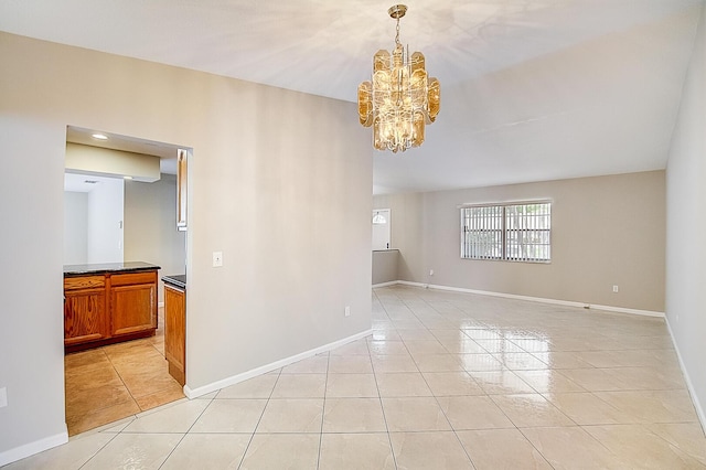 tiled spare room with a notable chandelier